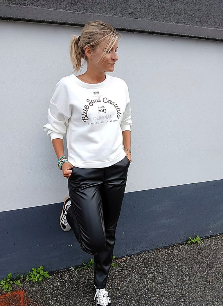 Pantalon simili cuir noir porté avec un sweat écru et des baskets